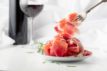 Prosciutto with rosemary and  red wine on a white wooden table.