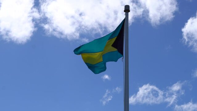 View of the Bahamas flag waving in the Caribbean wind, with blue sky 