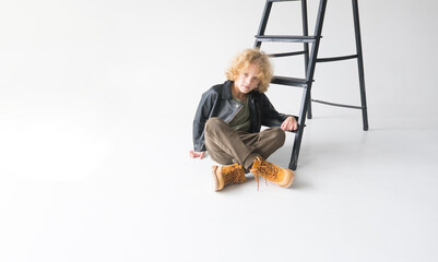 A Young Man with curly red hair Is Sitting Next To The Stairs