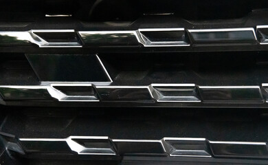 Close-Up of a Car's Black Grille with Chrome Accents - obrazy, fototapety, plakaty
