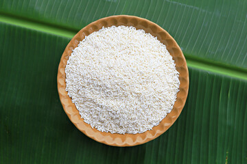 The glutinous rice seeds in the container are followed by green banana leaves 
