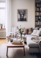 Bright airy living room with white walls, gray sofa, coffee table, books, plants and large photo of trees in water