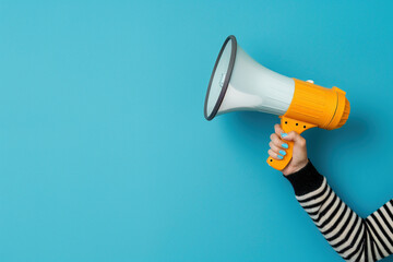 Hand Holding Megaphone on Blue Background with Space - obrazy, fototapety, plakaty