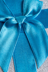 Blue satin ribbon on a silver background. Closeup.