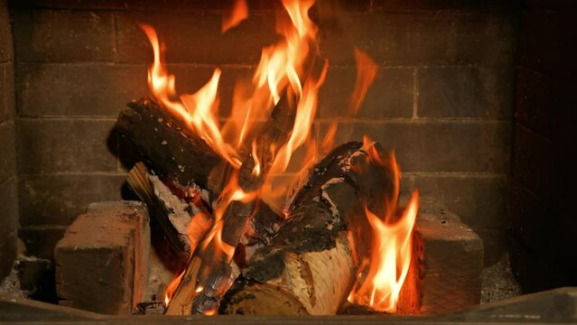 Home cozy fireplace with red flame and birch firewood. 4K video relaxing endless footage