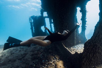 Sporty girl freediver exploring underwater the ruins of a ship. Free diving at wreck ship
