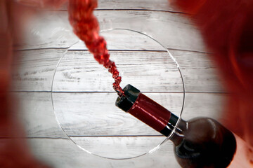 A wine glass is filled with red wine from a wine bottle, unusual perspective from inside the glass...