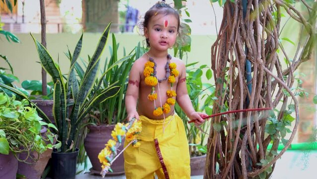 Cute Indian boy dresses as lord rama in action with bow at outdoor with from different angle at day