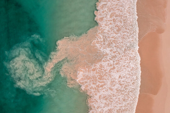 Top-down aerial view of pink sand and swirling turquoise surf on Pink Sands Beach, Harbour Island, Bahamas