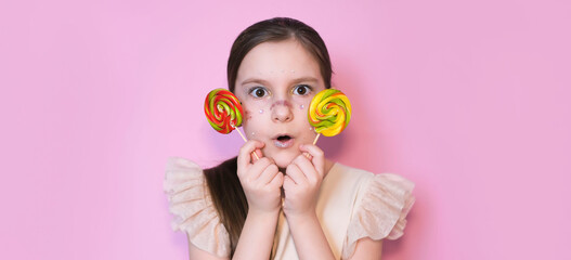 Banner. Portrait of an adorable surprised little girl with lollipop. Sugar for children. Little...