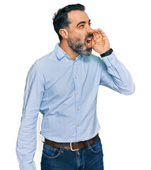 Middle aged man with beard wearing business shirt shouting and screaming loud to side with hand on mouth. communication concept.