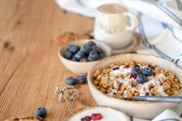 A breakfast dish of cereal, blueberries, and yogurt on a wooden table, free copy space