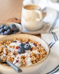 Granola, yogurt, blueberries served in a bowl on a table, vertical background of healthy cereal breakfast concept