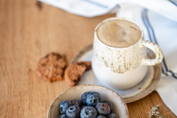 A coffee cup and blueberries in a bowl on a wooden table, coffe time, free copy space