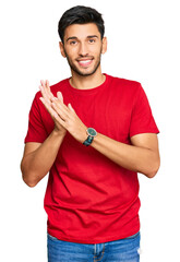 Young handsome man wearing casual red tshirt clapping and applauding happy and joyful, smiling...