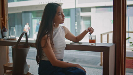 Serious woman waiting meeting in cafe close up. Chinese girl stirring lemonade