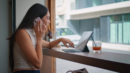 Chinese girl making call choosing purchases on laptop at coffeeshop close up. 