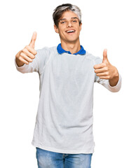 Young hispanic man wearing casual clothes approving doing positive gesture with hand, thumbs up smiling and happy for success. winner gesture.