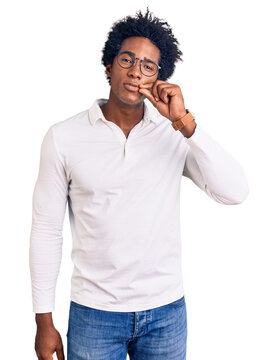 Handsome african american man with afro hair wearing casual clothes and glasses mouth and lips shut as zip with fingers. secret and silent, taboo talking