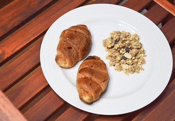 Small croissants on a white plate on a natural oak wood background