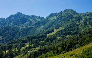 Beautiful panoramic mountain landscape with green trees and mountain slopes on a sunny summer day in Krasnaya Polyana in Russia