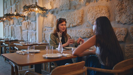 Young besties talking cafe modern interior. Attractive woman telling life story