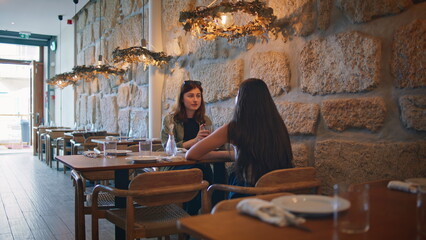 Friendly couple gossiping restaurant enjoying cozy atmosphere. Two women talking