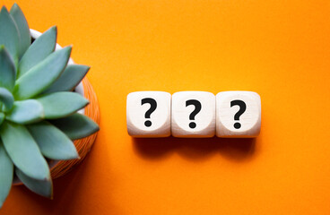 Question marks symbol. Concept words question mark on wooden cube. Beautiful orange background with...