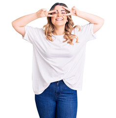 Fototapeta premium Young caucasian woman wearing casual clothes doing peace symbol with fingers over face, smiling cheerful showing victory