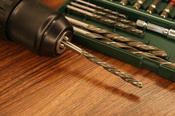 A drill and a set of drills on a dark wooden table. New drill and drill set.