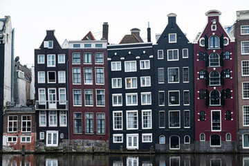 Iconic row of Amsterdam's canal houses, with their distinctive gabled facades and reflection in the calm waters, epitomizing Dutch urban architecture.