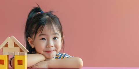 Young girl sitting at table with miniature house, ideal for real estate concept
