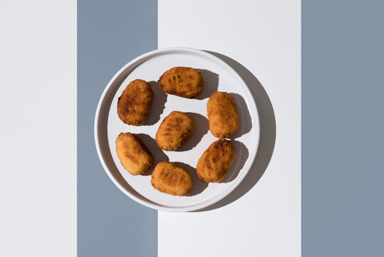 Fried croquettes on plate with shadowed backdrop - Powered by Adobe