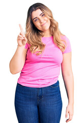 Young caucasian woman wearing sportswear showing and pointing up with finger number one while smiling confident and happy.