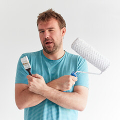Smiling man holding a brush and a roller in front of him