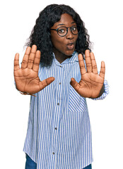 Beautiful african young woman wearing casual clothes and glasses moving away hands palms showing...