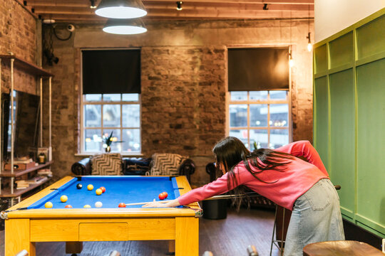 Young women playing pool in a cozy game room