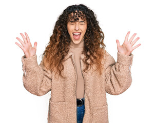 Young hispanic girl wearing winter clothes celebrating mad and crazy for success with arms raised...