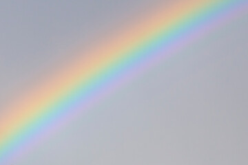 Pale rainbow in gray sky background texture