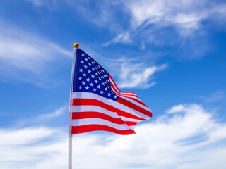 American national flag fluttering in the wind in front of blue sky with white clouds