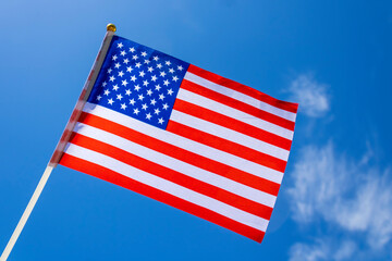 Flag of the United States in blue sky with white clouds
