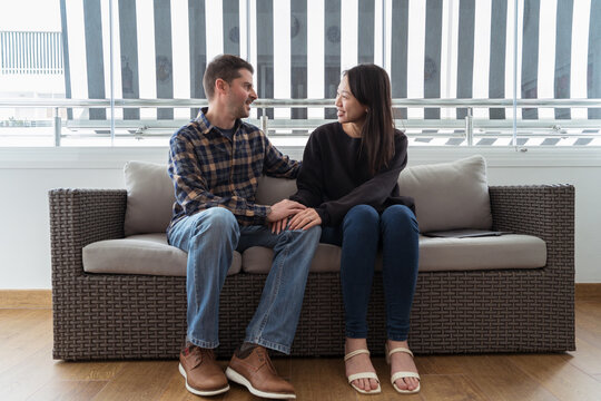 Joyful diverse couple conversing on sofa in a cozy setting