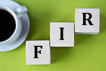 FIR - acronym on wooden big cubes on green background with cup of coffee