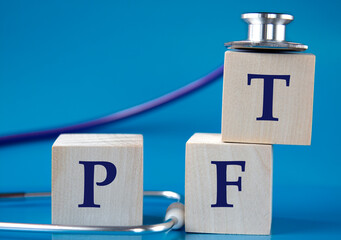 PFT - acronym on wooden large cubes on blue background with stethoscope