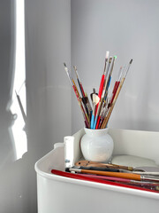 Paint brushes, spatula and artist material in a studio. Art supplies. Creative tools in a mobile cart.