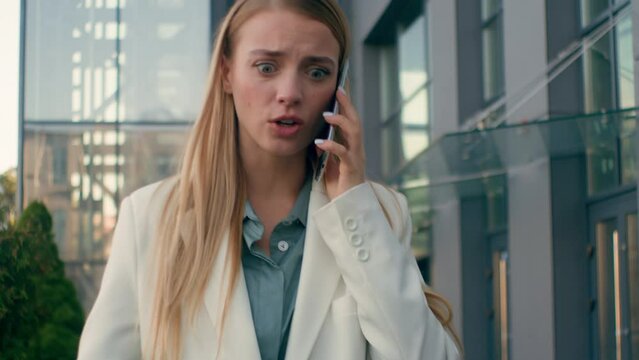 Upset frustrated angry stressed caucasian woman businesswoman walk on street near office talking arguing on mobile phone girl manager lady entrepreneur answer unpleasant business call using smartphone