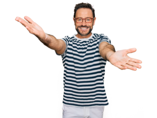 Middle age man wearing casual clothes and glasses looking at the camera smiling with open arms for hug. cheerful expression embracing happiness.