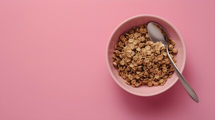 A bowl of cereal with a spoon on a pink surface. Suitable for breakfast concept 
