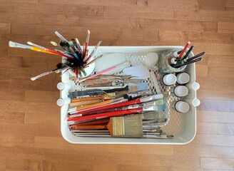 Paint brushes, spatula, paint tubes, and artist material in a studio. Art supplies. Creative tools in a mobile cart. Tool set seen from above.