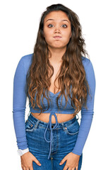 Young hispanic girl wearing casual clothes puffing cheeks with funny face. mouth inflated with air, crazy expression.